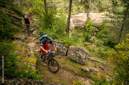 Two mountain bikers on a narrow forest trail in the low Pyrenees. Huesca, Spain.