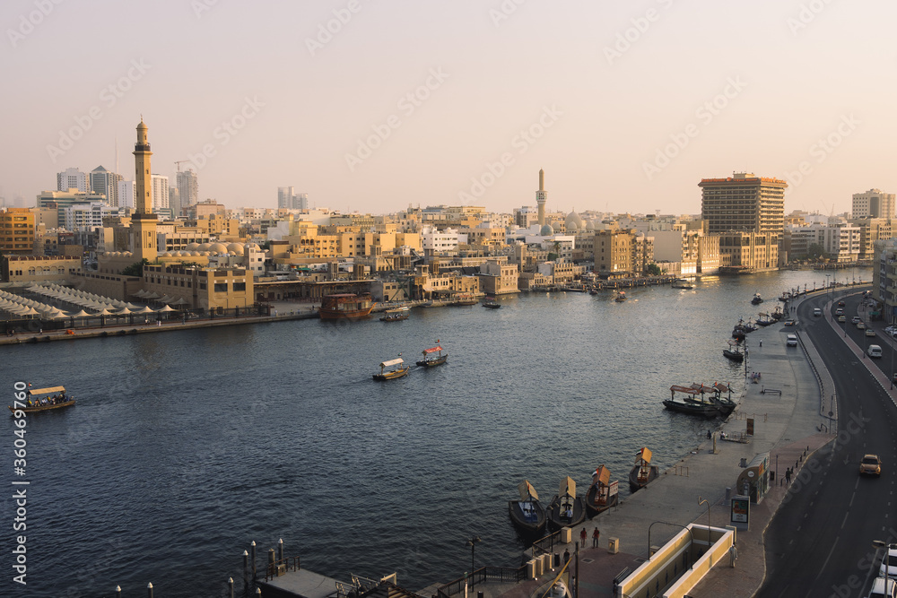 Landscape shot of Old Dubai, with a docked dhow cruise and a couple abra's. Dubai reopens concept. 