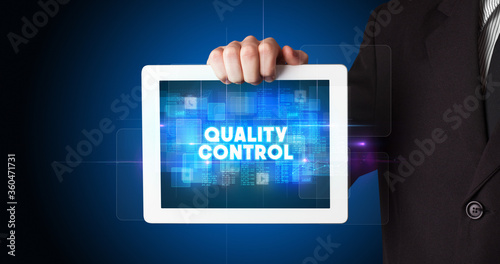Wallpaper Mural Young business person working on tablet and shows the inscription: QUALITY CONTROL Torontodigital.ca