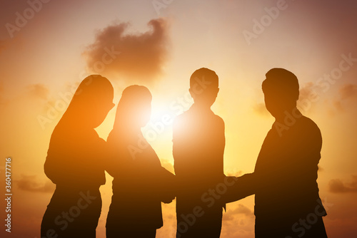 Silhouette of business teamwork and happy of success in sunset evening sky background.