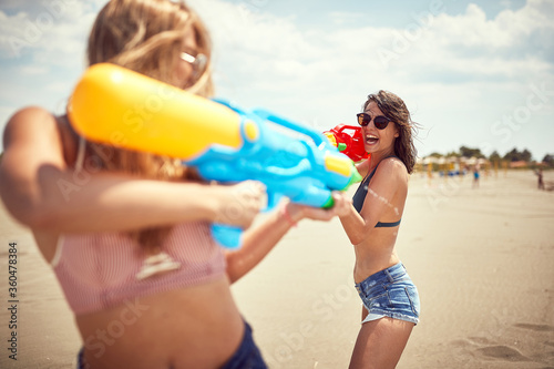 Sexy girls playing with water gun.Crazy vacation at the beach in summer holiday.