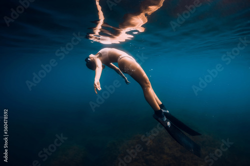 Woman free diver with fins relaxing underwater in ocean. Woman and reflection