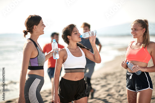 Young fitness womans drinking water by the sea.