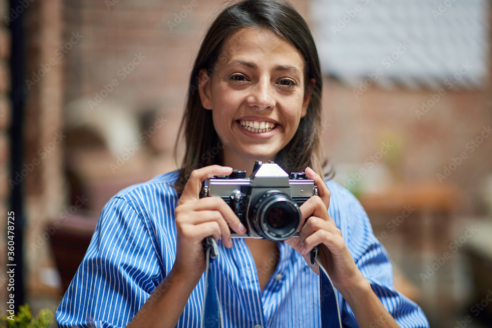 beautiful young caucasian female holding retro camera, smiling,  eye contact