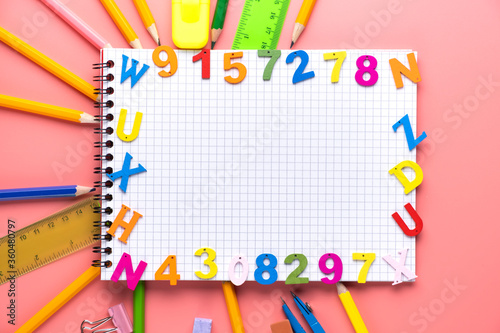Many different school supplies and empty notepad white sheet of paper on pink copy space background. Back to school concept.