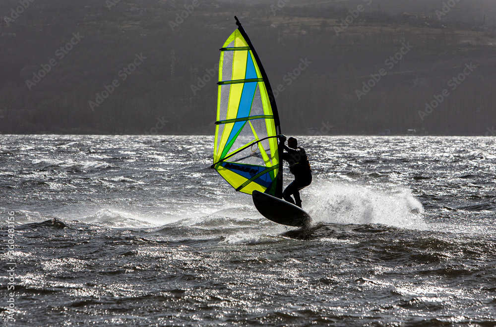 Windsurfer riding waves at sunny windy day. Windsurfing, extreme sport. Contrasting image