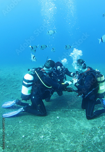 Diving instructor and group students in underwater exercise. Instructor teaches students to admire. Underwater scuba diving education and training.