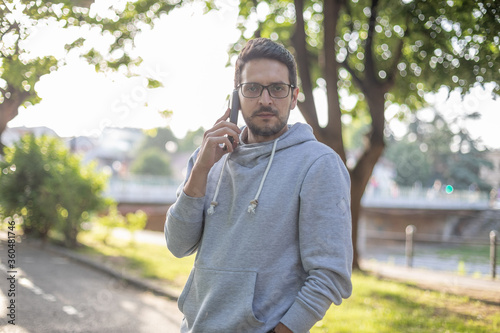 Smart looking man on smartphone in park, back light