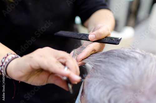 Manos de peluquera cortando pelo con canas