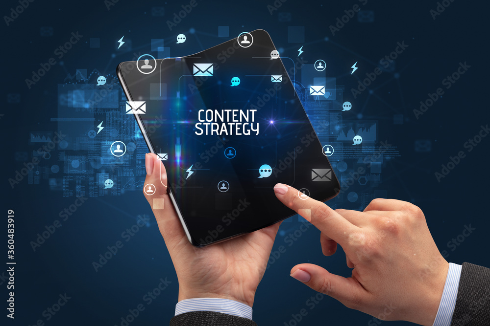 Businessman holding a foldable smartphone with CONTENT STRATEGY inscription, social networking concept