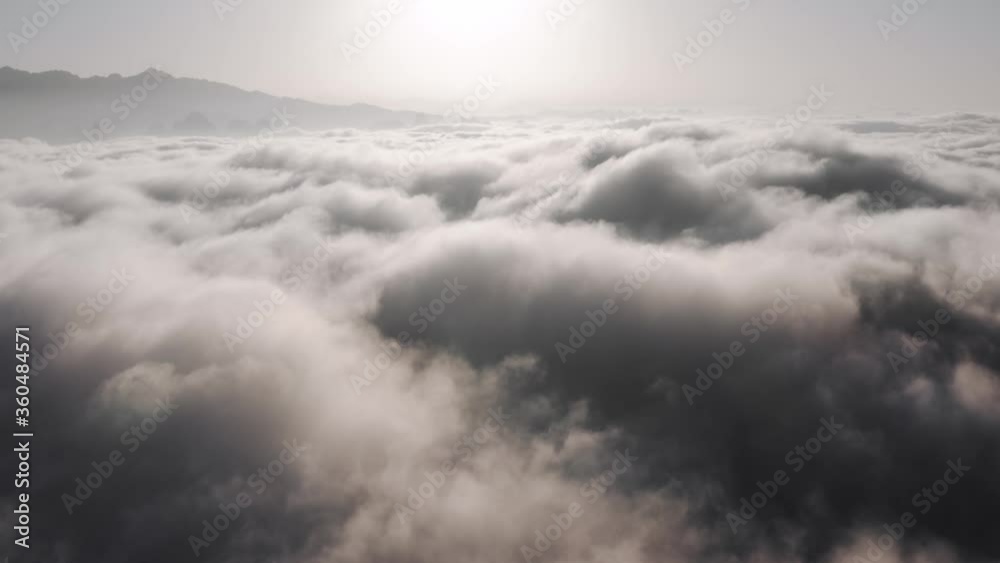Aerial view above thick clouds rolling over mountain peaks Aerial view above thick clouds rolling over mountain peaks