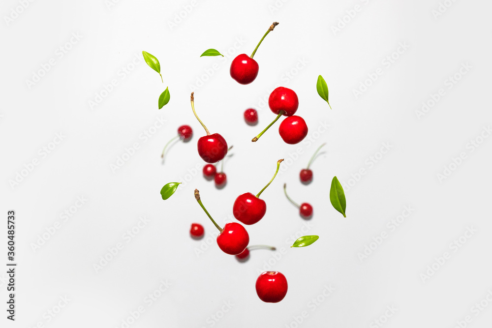 Ripe cherry berry with green leaves levitating on grey background. Berry summer background. Flat lay, top view Ripe cherry berry with green leaves levitating on grey background. Berry summer background. Flat lay, top view