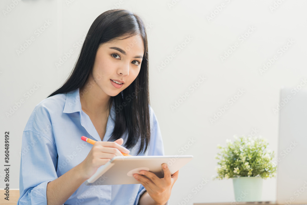 Beautiful asian women conferencing work from home with tablet taking on headphones in the morning. Smiling charming happy young female stay at home. Beautiful asian women conferencing work from home with tablet taking on headphones in the morning. Smiling charming happy young female stay at home.