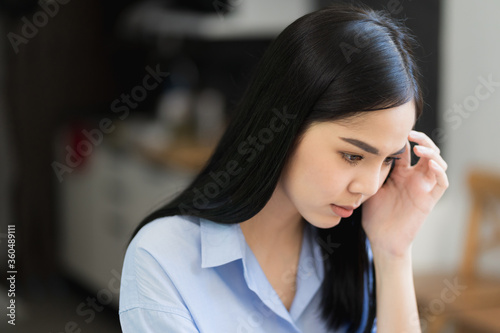 Depressed asian woman feeling suffer head in hands and headache.