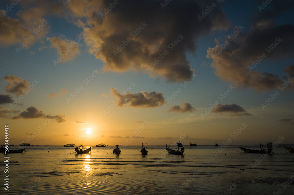 Beautiful sunset on tropical island, Koh Tao, Thailand. Boats in low tide water, yellow clouds