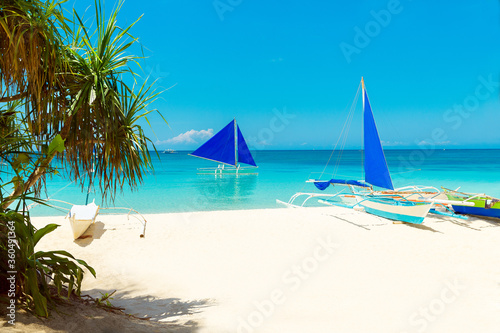 Beautiful landscape of tropical beach on Boracay island, Philippines. Coconut palm trees, sea, sailboat and white sand. Nature view. Summer vacation concept.