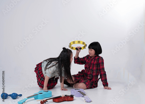 Elder sister holding Tambourine in hand and taliking with Younger sister,doing activity together,happy time photo