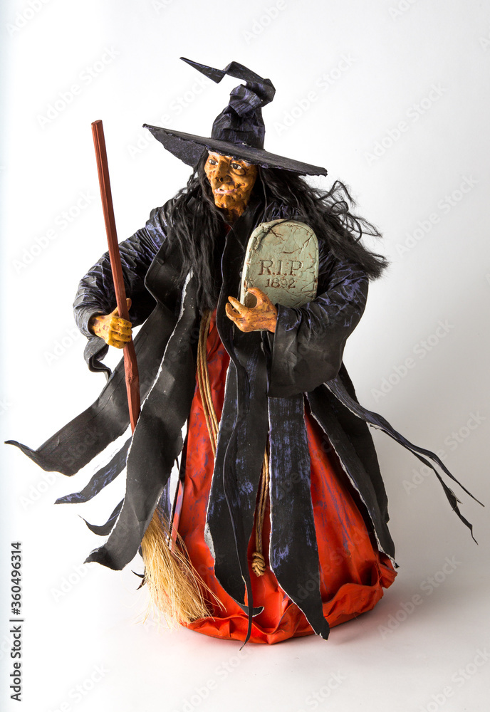 Fototapeta a witch figurine with a broom on an isolated white background.