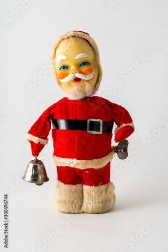 a vintage styalized Santa Claus toy figurine on an isolated white background. Wind-up toy with bell that rings. photo
