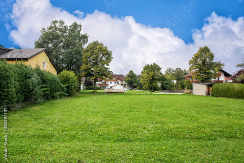 A traditional European countryside with a large green lawn under blue cloudy sky.
