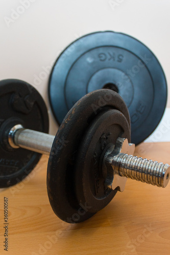 Dumbbell with black discs on wooden platform. Training at home concept. Home training