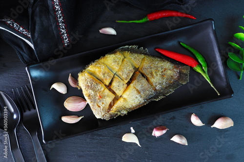 Thai crispy gourami fish or Sepat Siam fish or Pla salid in Thai language displayed on the black dish photo