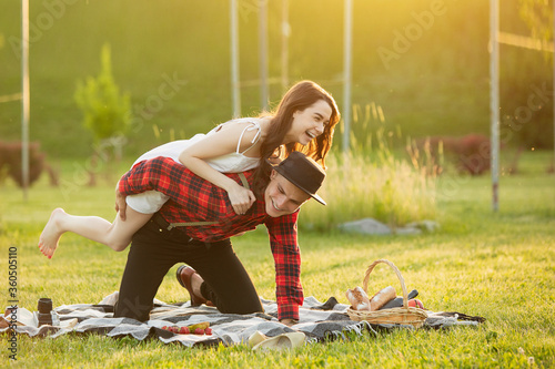 Laughting, having fun. Caucasian young couple enjoying weekend together in the park on summer day. Look lovely, happy, cheerful. Concept of love, relationship, wellness, lifestyle. Sincere emotions. photo