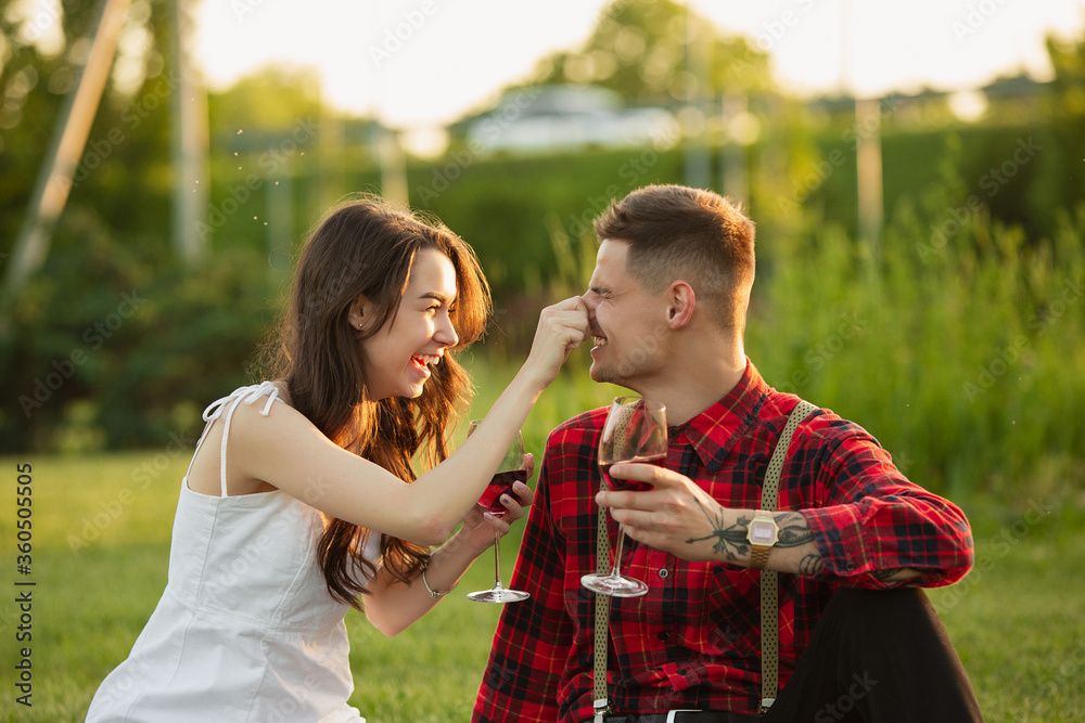 Fototapeta premium Laughting, having fun. Caucasian young couple enjoying weekend together in the park on summer day. Look lovely, happy, cheerful. Concept of love, relationship, wellness, lifestyle. Sincere emotions.