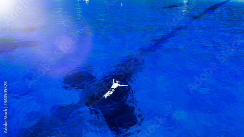 Aerial view of swimmer swimming in the crystal clear ocean