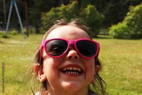 Little girl in beautiful pink sun glasses. A child in the summer in pink sunglasses.