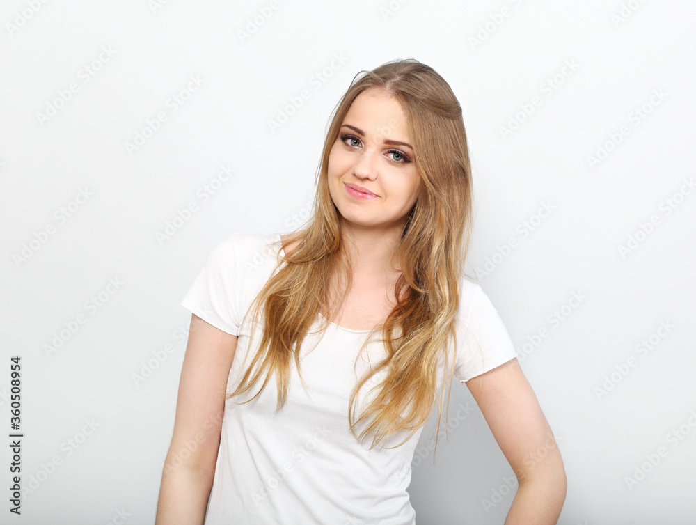 Pretty smiling young woman with fair blond long hair in casual dress, blue jeans and t-shirt. Studio shot of good looking beautiful woman isolated against grey studio wall Pretty smiling young woman with fair blond long hair in casual dress, blue jeans and t-shirt. Studio shot of good looking beautiful woman isolated against grey studio wall