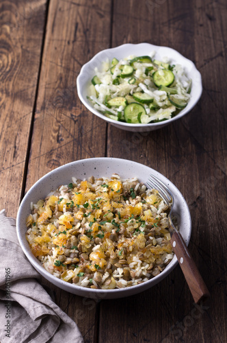 Traditional Middle Eastern dish, Mujadara of lentils, rice and fried onions with a salad of cabbage and cucumbers on wooden table, top view, selective focus, space	 photo