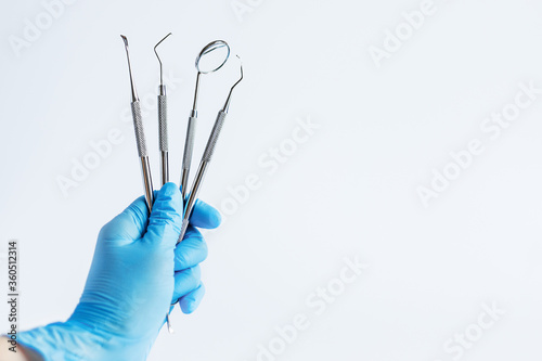 Doctor's hand holding dentistry tools for teeth dental care and treatment over white background.