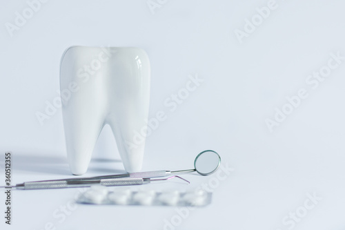 Model of white tooth, medical pills and dentistry tools on white background.