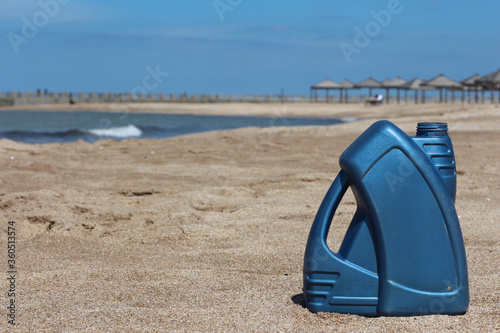 Blue plastic canister of motor oil on the beach.