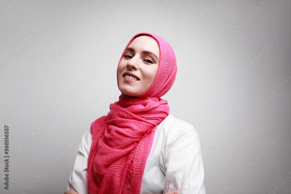 Close-up portrait of young and happy Muslim woman in hijab against wall. Space for text. Close-up portrait of young and happy Muslim woman in hijab against wall. Space for text.