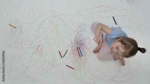 Little girl waves hello and sends an air kiss on the pencil-drawn floor . High quality 4k footage