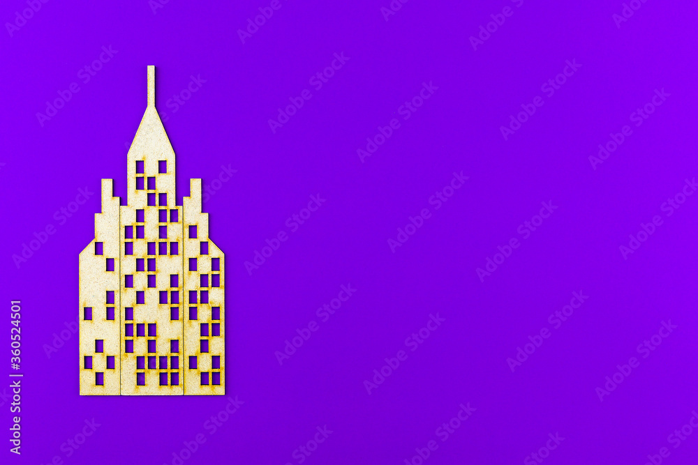 House skyscraper cut out of cardboard on purple background with copy space on the right.