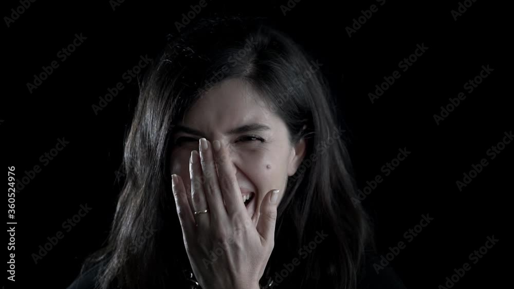 Happy, joyful beautiful woman is laughing on black background, studio shot. Happy and positive face concept.