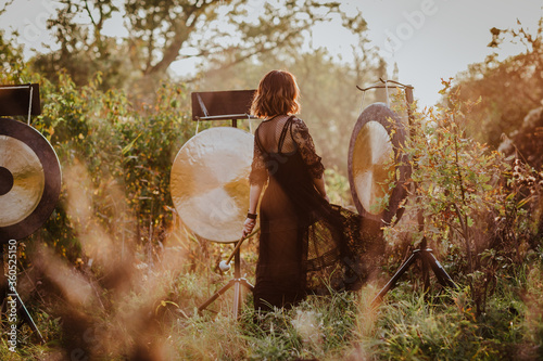 Young woman in black dress posing with Hong in the forest. Sunset.