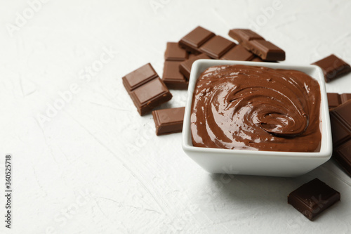 Bowl with chocolate and chocolate pieces on white background