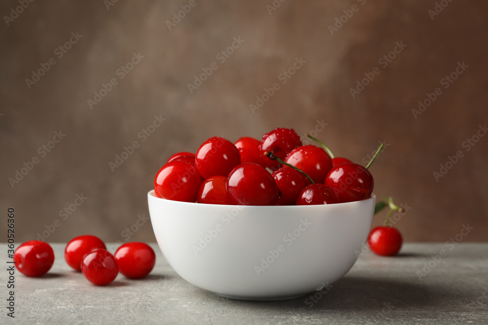 Bowl with red cherry on gray table, space for text Bowl with red cherry on gray table, space for text