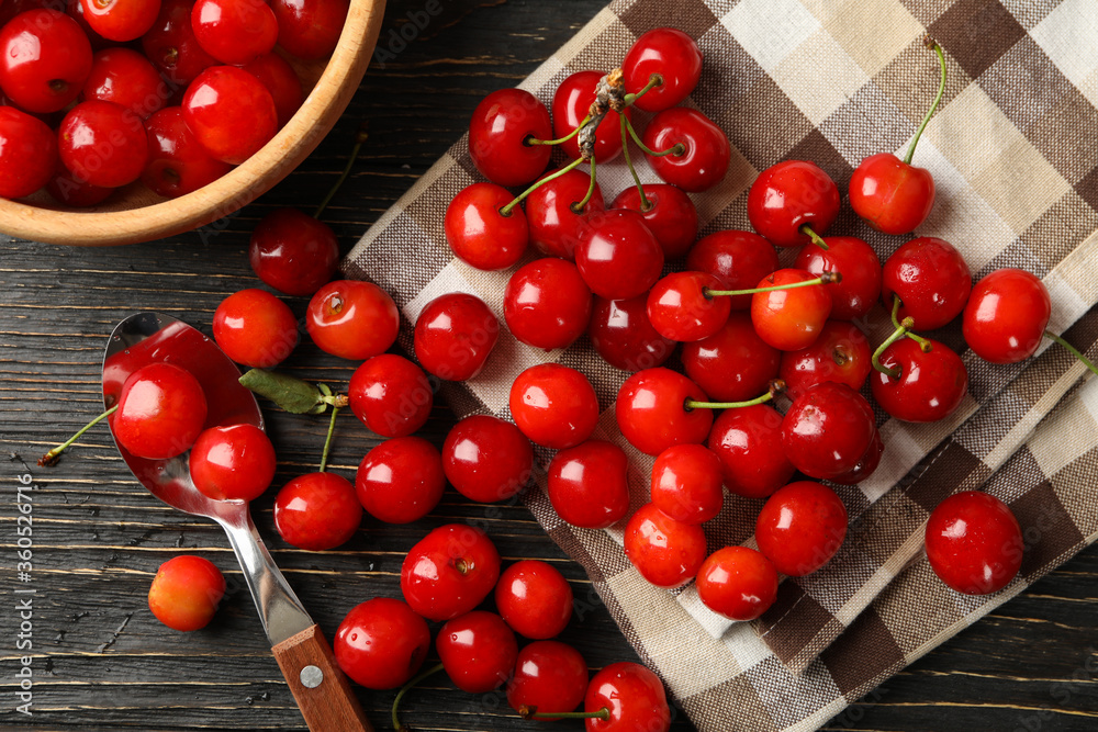 Towel, spoon and bowl with cherry on wooden background, top view Towel, spoon and bowl with cherry on wooden background, top view