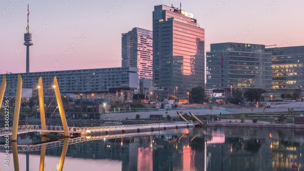 Donaustadt Danube City night to day transition timelapse is a modern quarter with skyscrapers and business centres in Vienna, Austria. Modern architecture and pedestrian bridge illuminated at morning Donaustadt Danube City night to day transition timelapse is a modern quarter with skyscrapers and business centres in Vienna, Austria. Modern architecture and pedestrian bridge illuminated at morning