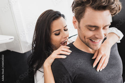 Selective focus of beautiful woman embracing smiling boyfriend in kitchen