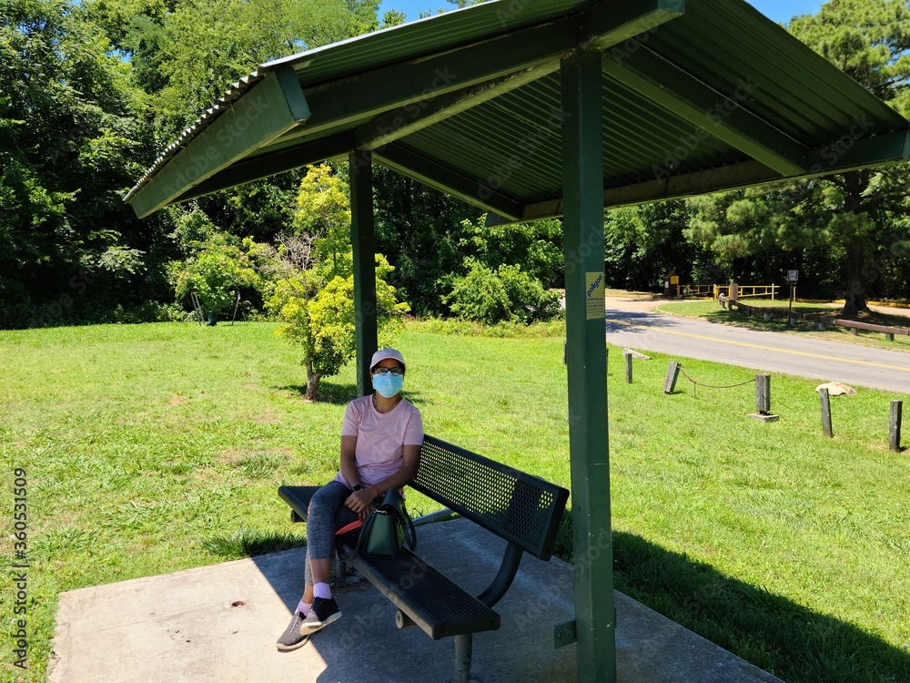 A person sits in the park seats with wearing face masks to prevention of infectious disease. A person sits in the park seats with wearing face masks to prevention of infectious disease.