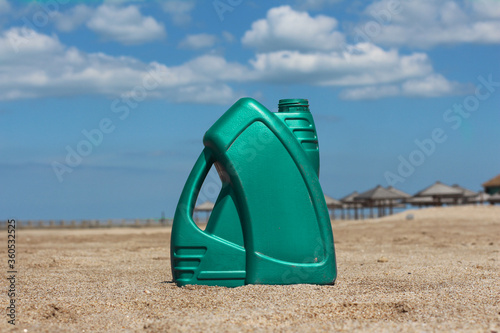 Colored plastic canister of motor oil on the beach. Green, Gold, Purple, Gray, Blue, Red, White.