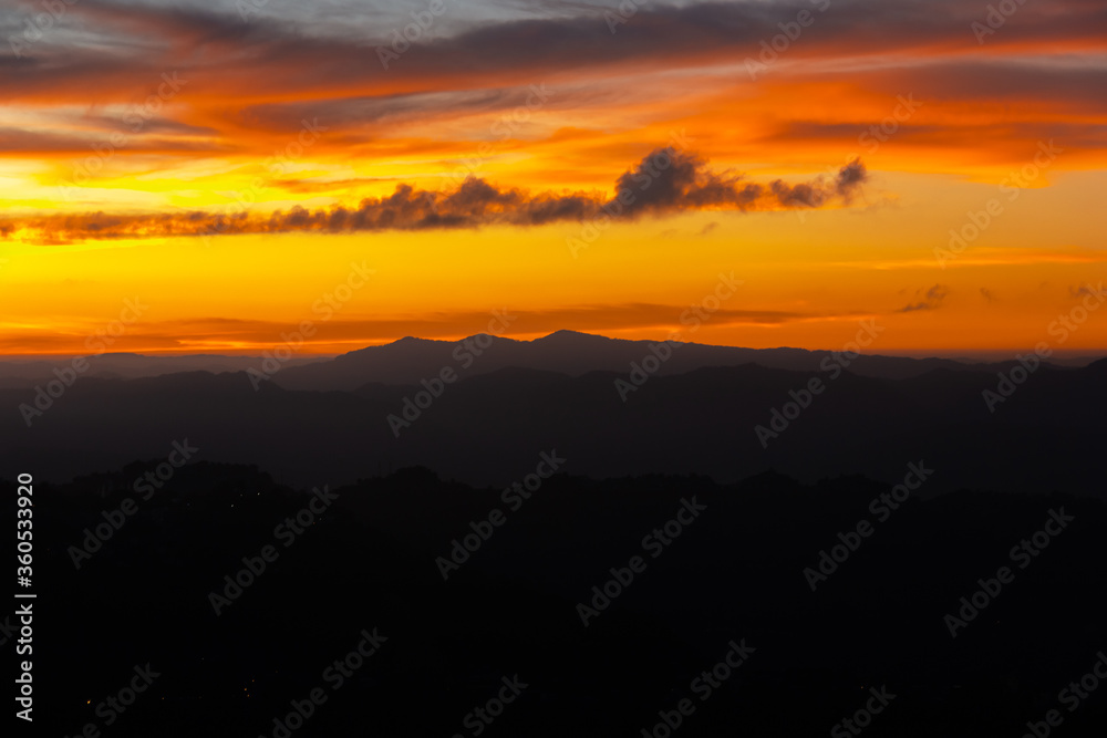 Sunset colours in the sky above silhouetted mountains in the city of Aizawl in Mizoram.