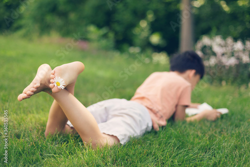 young boy reading a book in a meadow