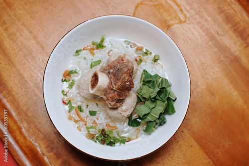 meatball soup with vermicelli and beef ribs. indonesian street food. white bowl. pieces of mustard leaf